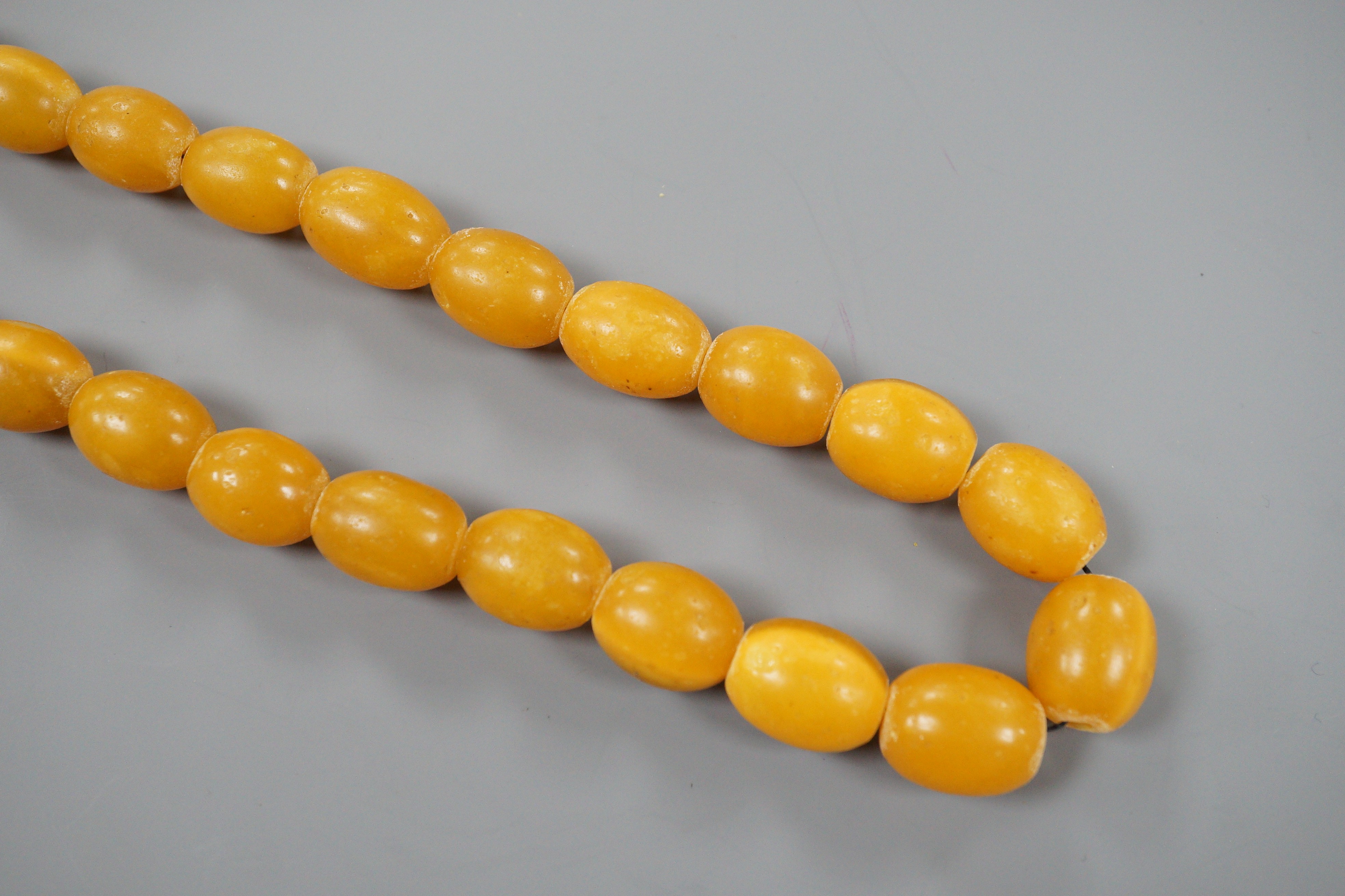 A singe strand oval amber bead necklace, 56cm, gross 68 grams.